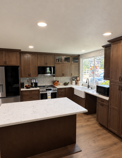 Completed kitchen remodel in Shingle Springs, CA featuring dark stained shaker cabinets, white quartz countertops, large center island and stainless steel appliances