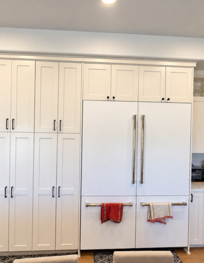 Completed kitchen renovation featuring floor-to-ceiling white shaker cabinets, built-in refrigerator and custom storage