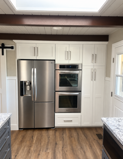Custom white shaker kitchen cabinets surrounding stainless steel refrigerator and double wall ovens in Cameron Park, CA