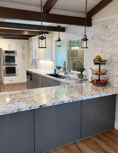 Completed Cameron Park kitchen remodel featuring large granite peninsula, gray shaker cabinets and pendant lighting