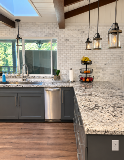 Renovated kitchen with stainless steel sink, granite countertops, gray shaker cabinets and large breakfast peninsula