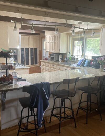 Kitchen peninsula with raised granite breakfast bar and outdated cabinetry before renovation in Cameron Park, CA