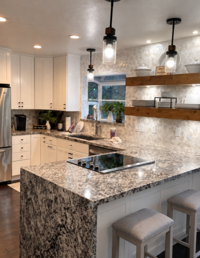Finished kitchen remodel in Cameron Park, CA featuring a large island, custom floating shelves and hexagonal tile backsplash.