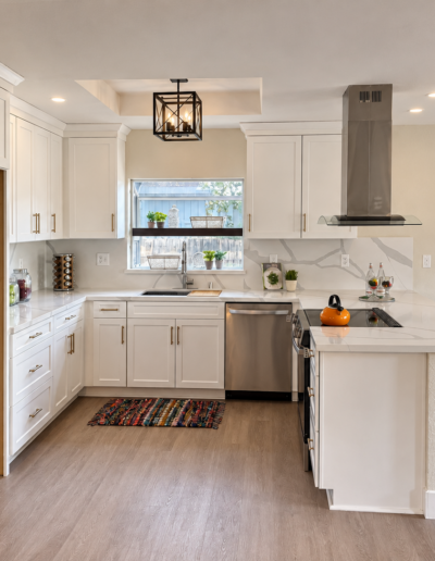Completed Cameron Park kitchen remodel featuring modern white cabinetry, updated countertops, tile backsplash and stainless steel island range hood