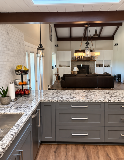 Open-concept kitchen remodel in Cameron Park, CA featuring granite peninsula, pendant lighting and vaulted ceiling with exposed wood beams