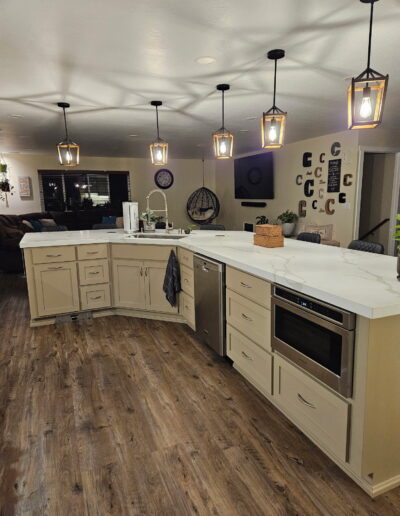 Relocated kitchen in Cameron Park featuring an expansive island, stainless steel dishwasher, built-in microwave and wood-look plank flooring.