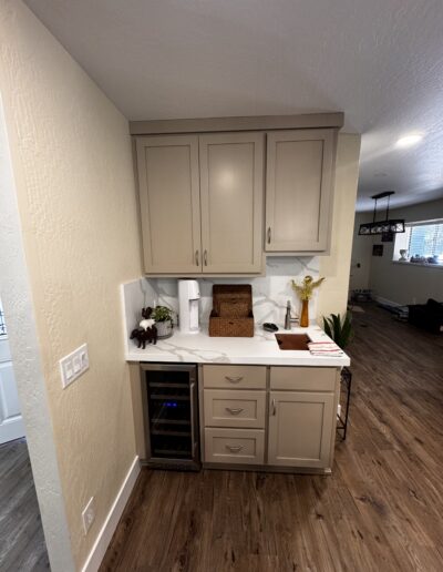 Custom wet bar in Cameron Park, CA featuring taupe shaker cabinetry, white quartz-look countertops, undermount sink and built-in beverage refrigerator.